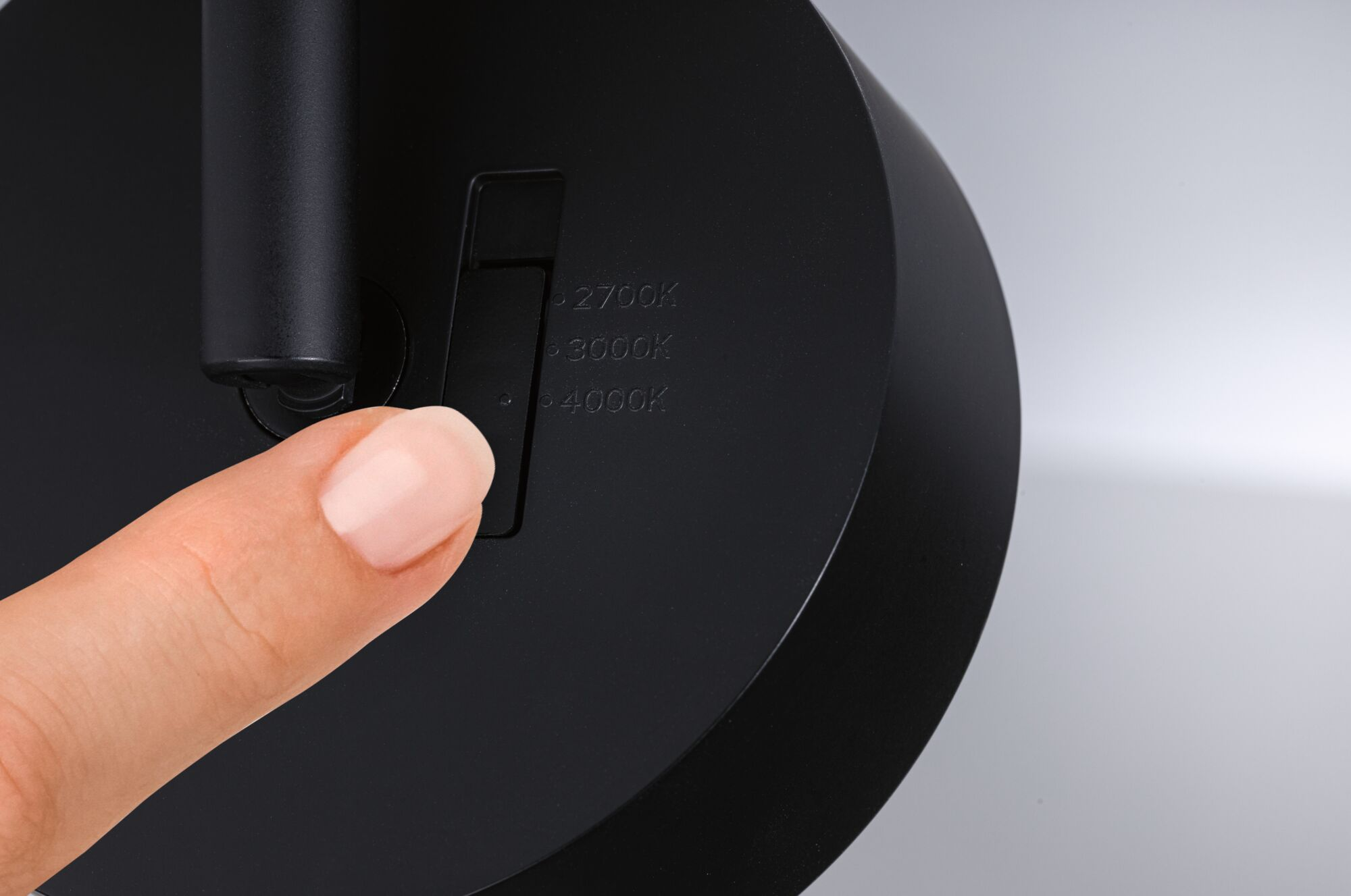 Palec dotyka przełącznika z oznaczeniami 2700K, 3000K i 4000K.