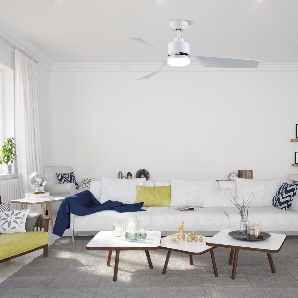 Un ventilador de techo blanco con luz sobre un sofá con cojines.