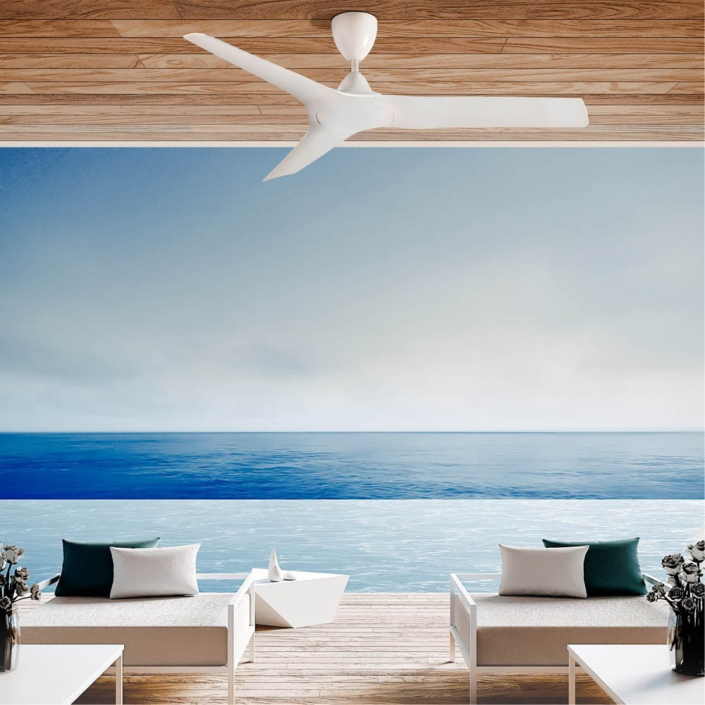 Un ventilador de techo blanco sobre una piscina infinita con vistas al mar.