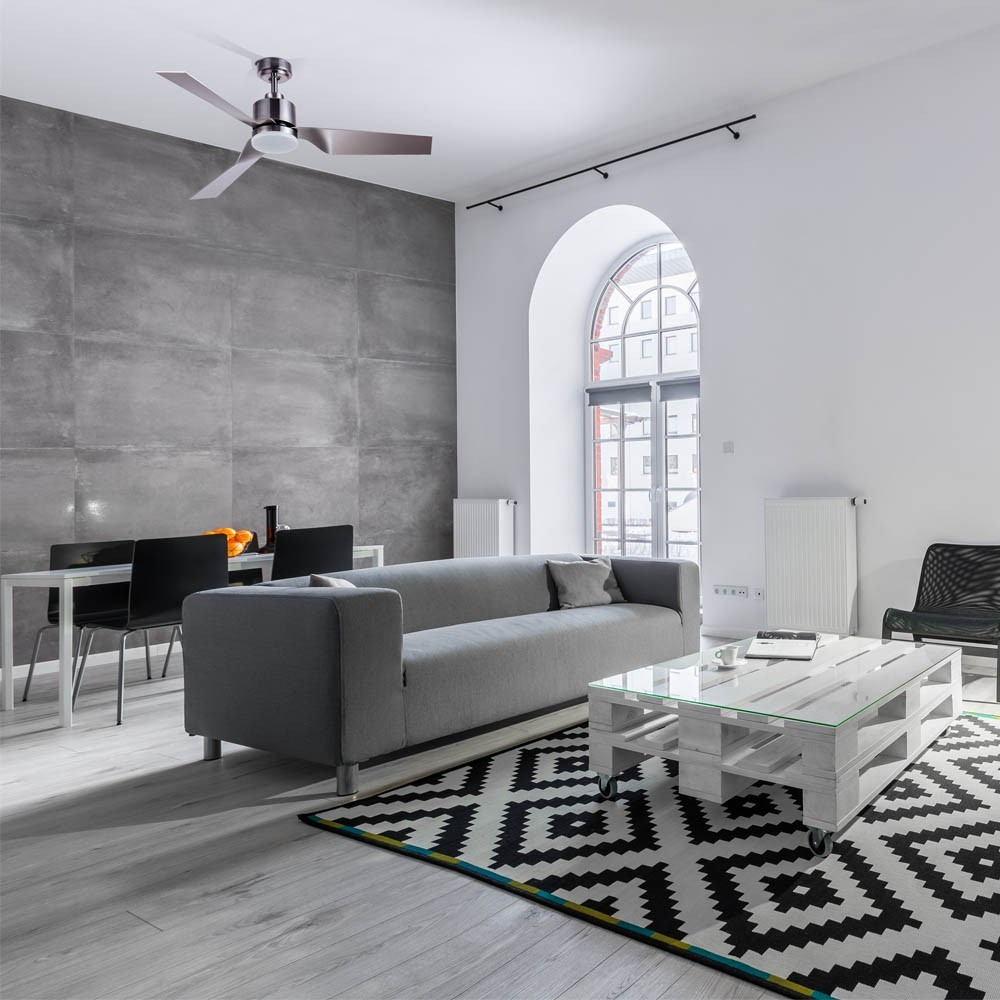 Sala de estar moderna con sofá gris, mesa de centro, alfombra, mesa de comedor y ventilador.