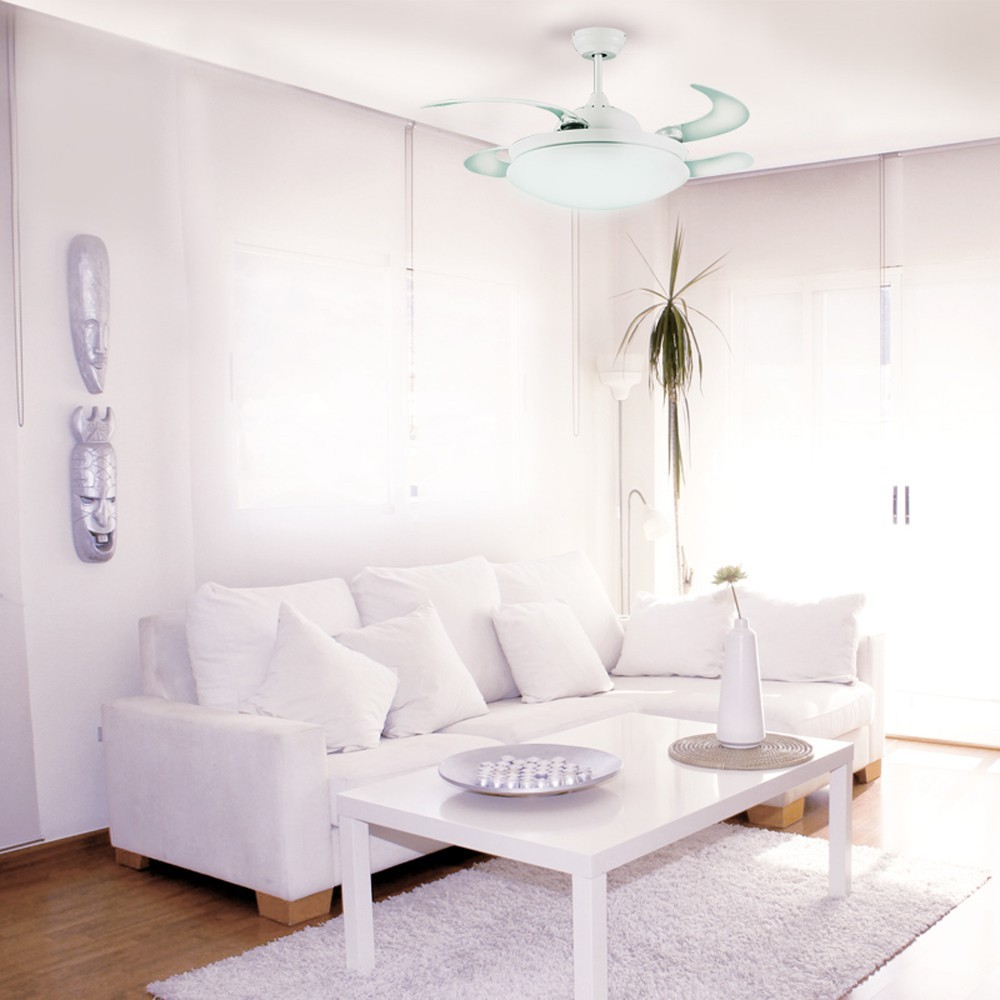 Una sala de estar blanca con sofá, mesa de centro, ventilador de techo y decoración.