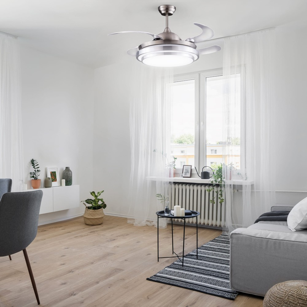 Un ventilador de techo con luz sobre una ventana con cortinas y muebles.