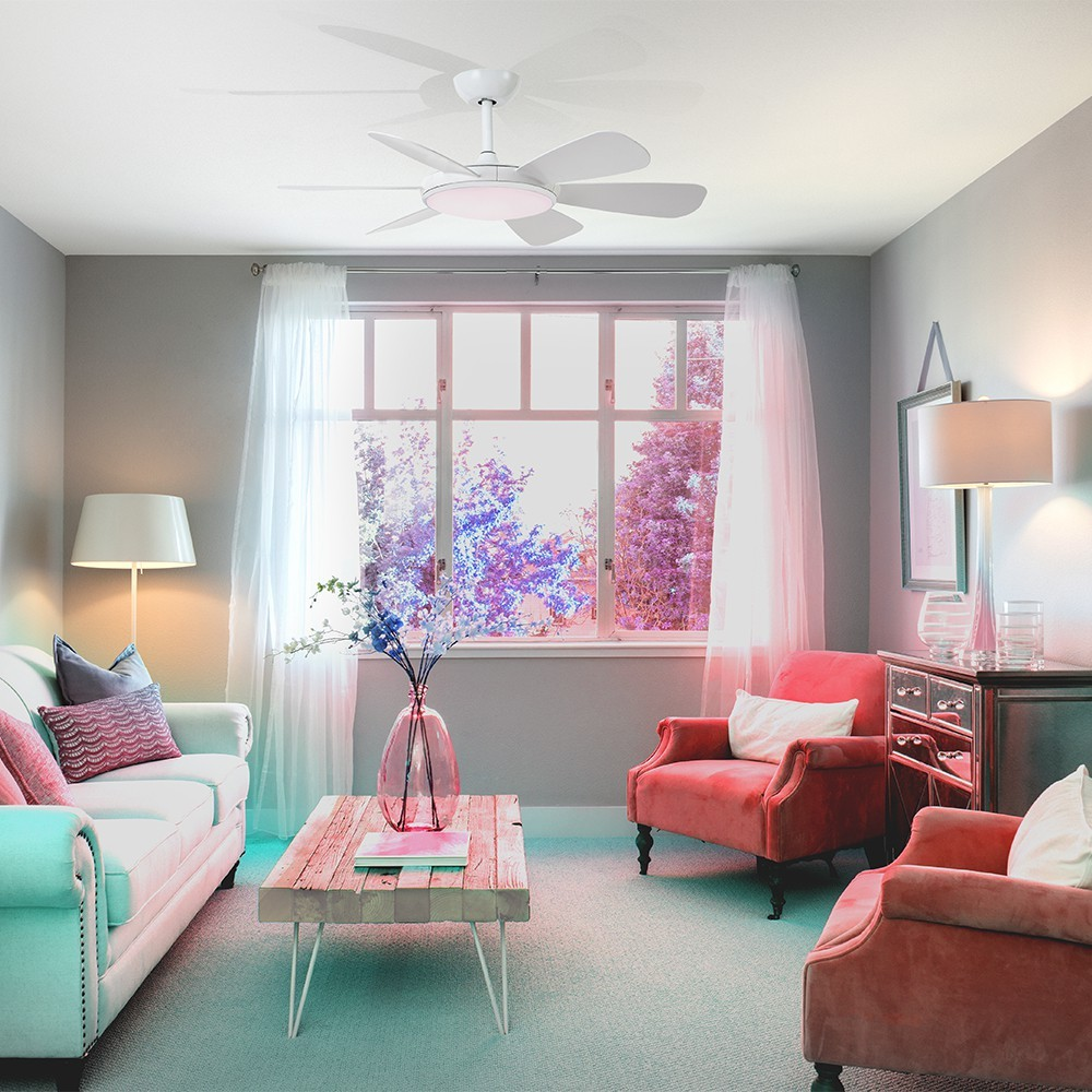 Una sala de estar con sofá, dos sillones coral, mesa de madera y ventilador de techo.