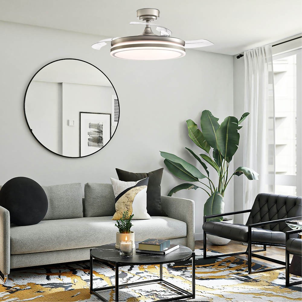 Una sala de estar moderna con sofá gris, sillón negro, espejo redondo y planta grande.