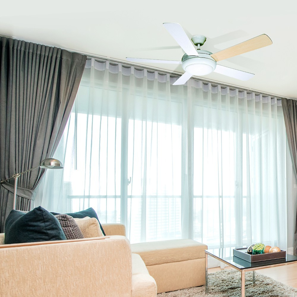 Una sala de estar con sofá, ventilador de techo, cortinas y ventanas.