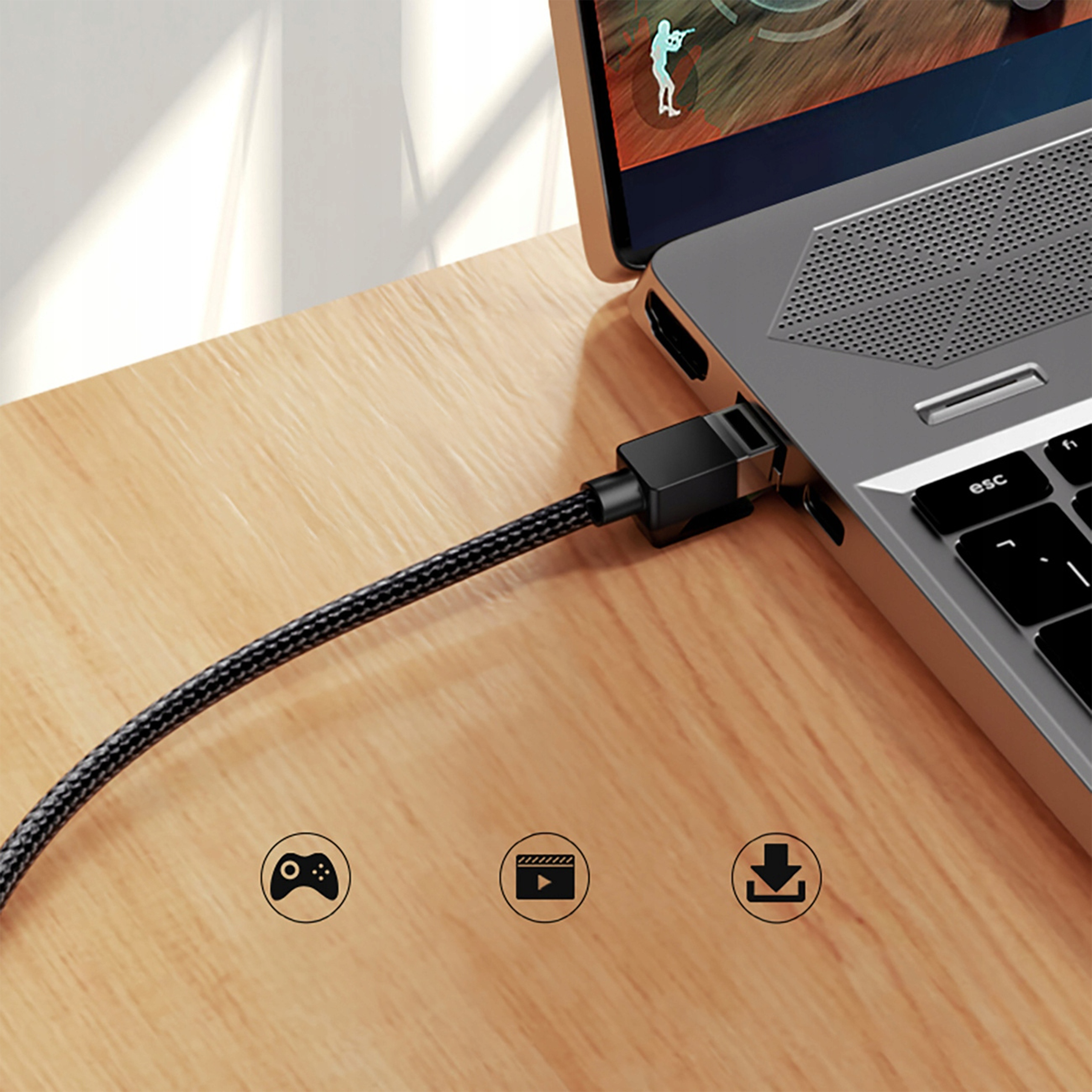 Czarny kabel łączy laptop z ikonami gier, wideo i pobierania.