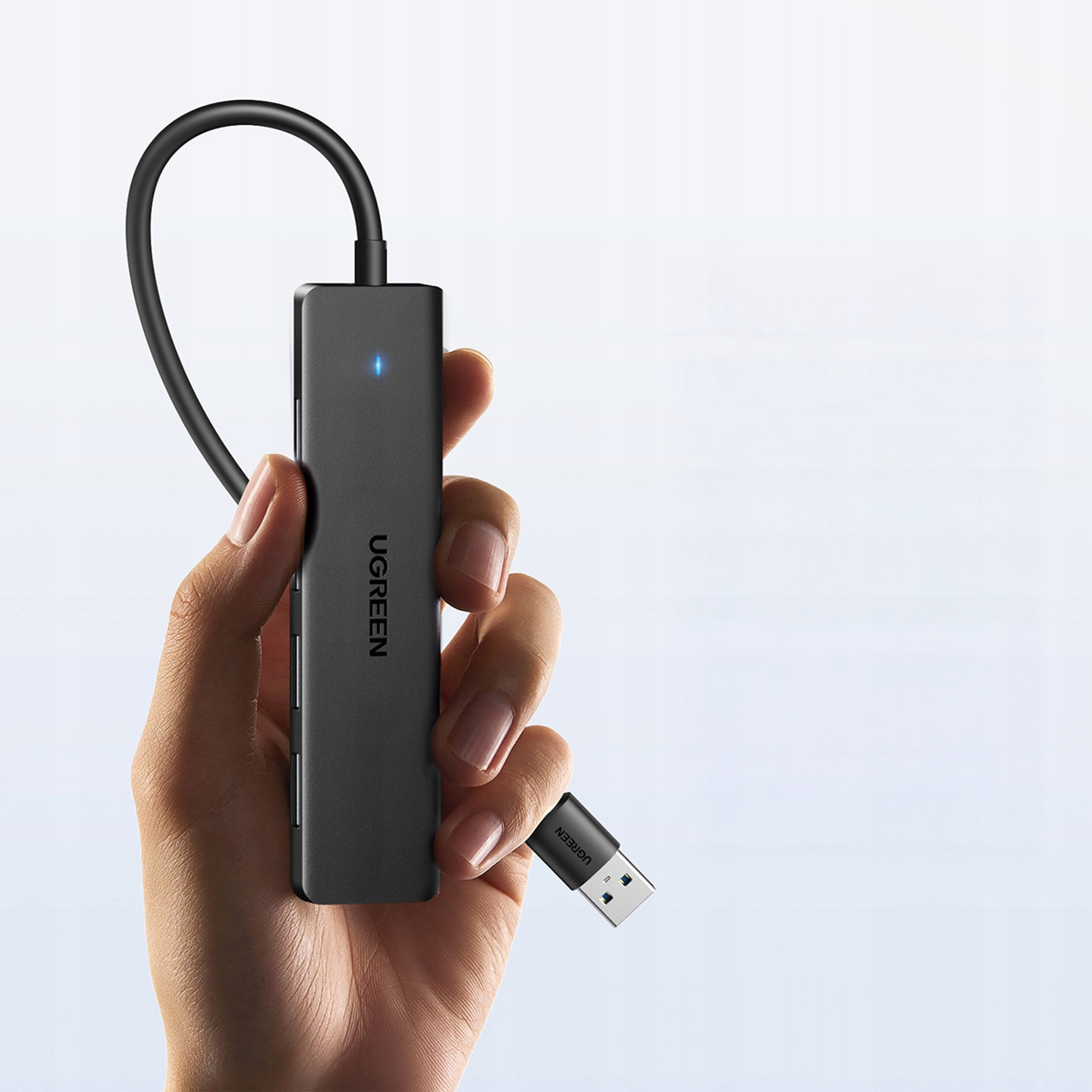 Dłoń trzyma czarny hub USB-C z małym niebieskim światełkiem.