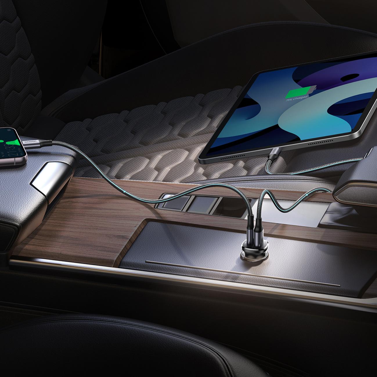 Telefon i tablet ładują się w samochodzie przez kable podłączone do ładowarki.