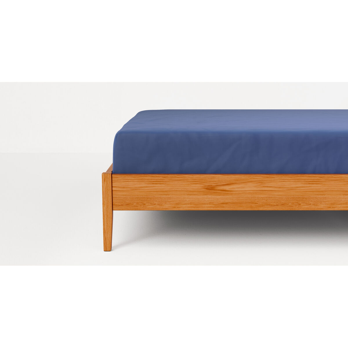 Una sábana azul sobre un marco de cama de madera.