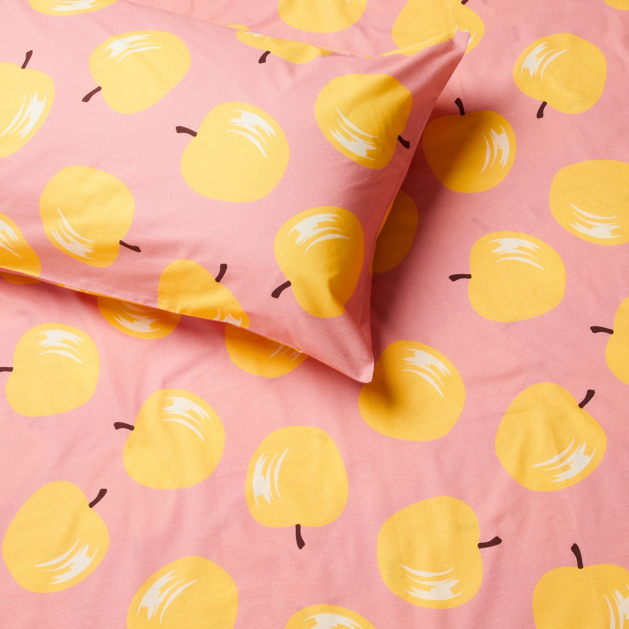 Ropa de cama rosa con manzanas amarillas y tallos marrones.