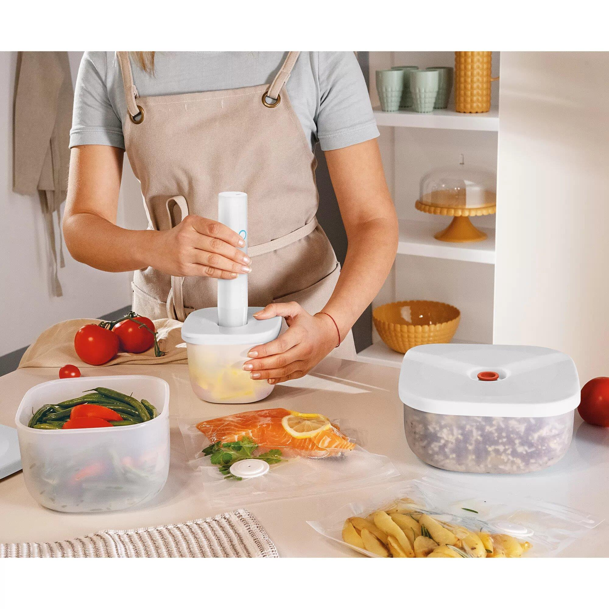 Una persona usa una selladora al vacío en una cocina con alimentos.