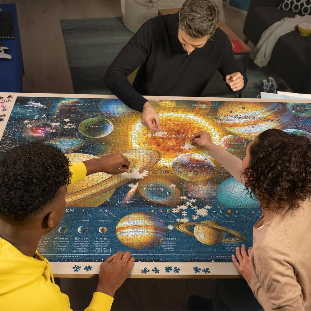 Trois personnes assemblent un puzzle du système solaire avec planètes et étoiles.