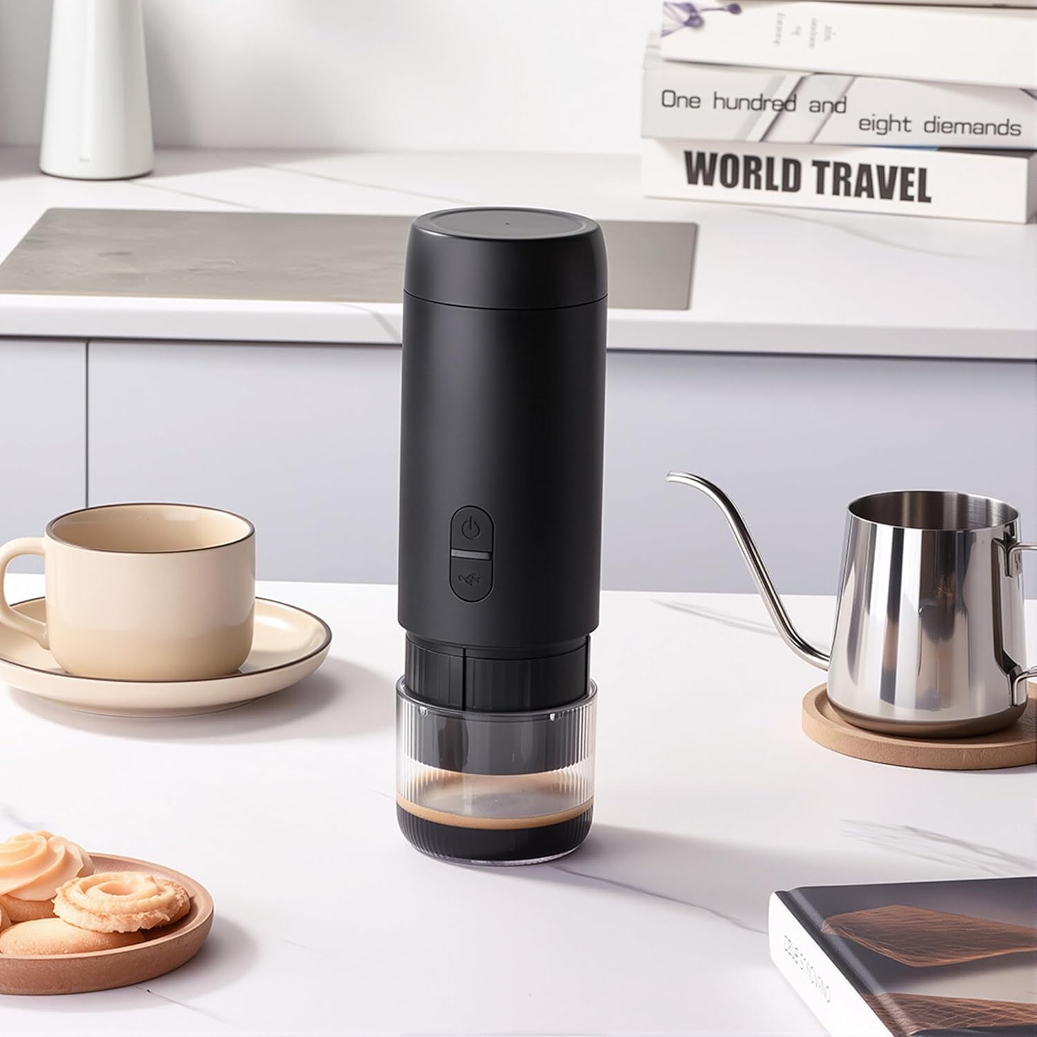 Eine schwarze Kaffeemaschine mit einem Glasbehälter steht neben einer Tasse und Keksen.