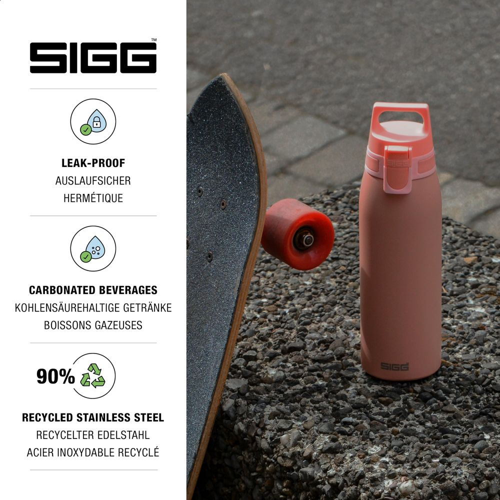 Eine rosafarbene SIGG-Flasche und ein Skateboard auf Steinen.