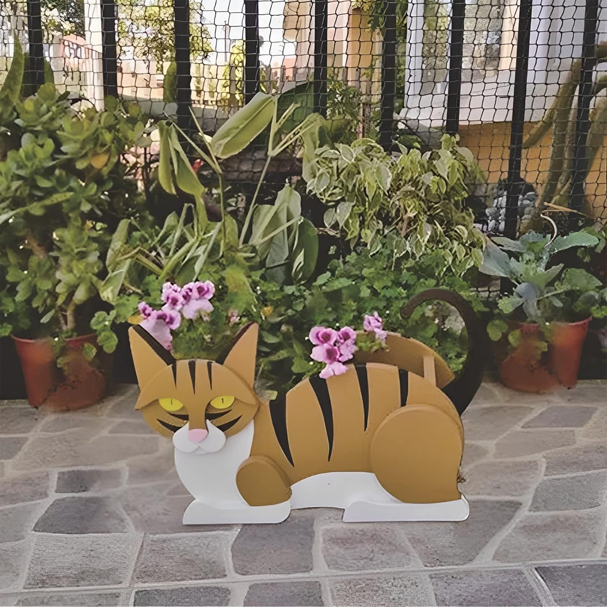 Ein hölzerner Katzenblumentopf mit lila Blumen steht auf einer gepflasterten Terrasse.