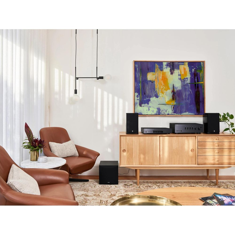 Ein Wohnzimmer mit braunen Ledersesseln, einem Holzbüffet mit Stereoanlage und Kunst an der Wand.