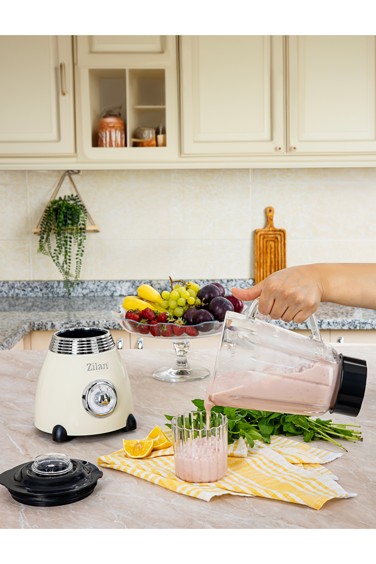 Kremalı bir smoothie blenderdan bardağa dökülüyor. Meyve görünüyor.