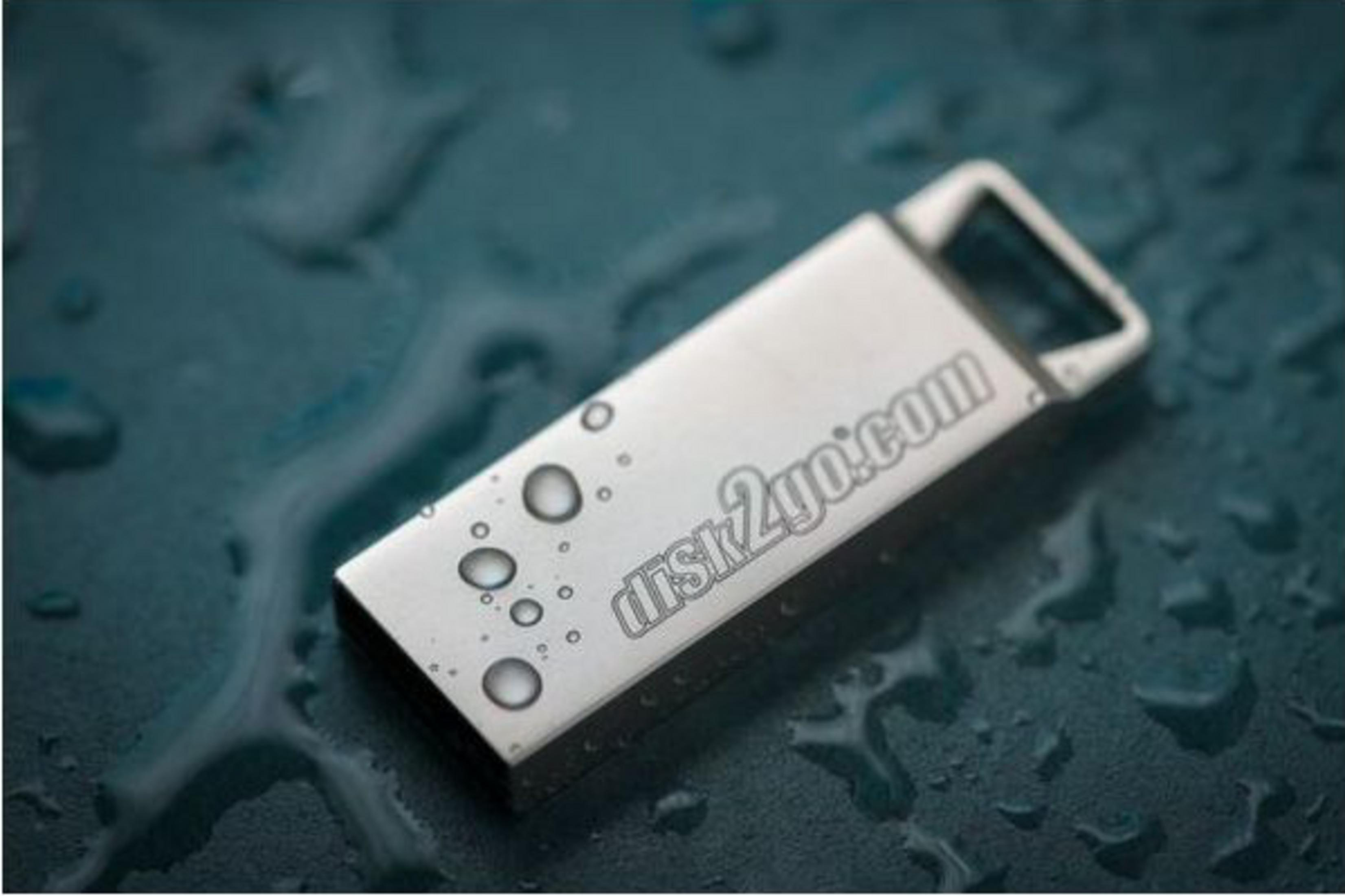 Une clé USB argentée avec des gouttes d'eau sur une surface sombre.