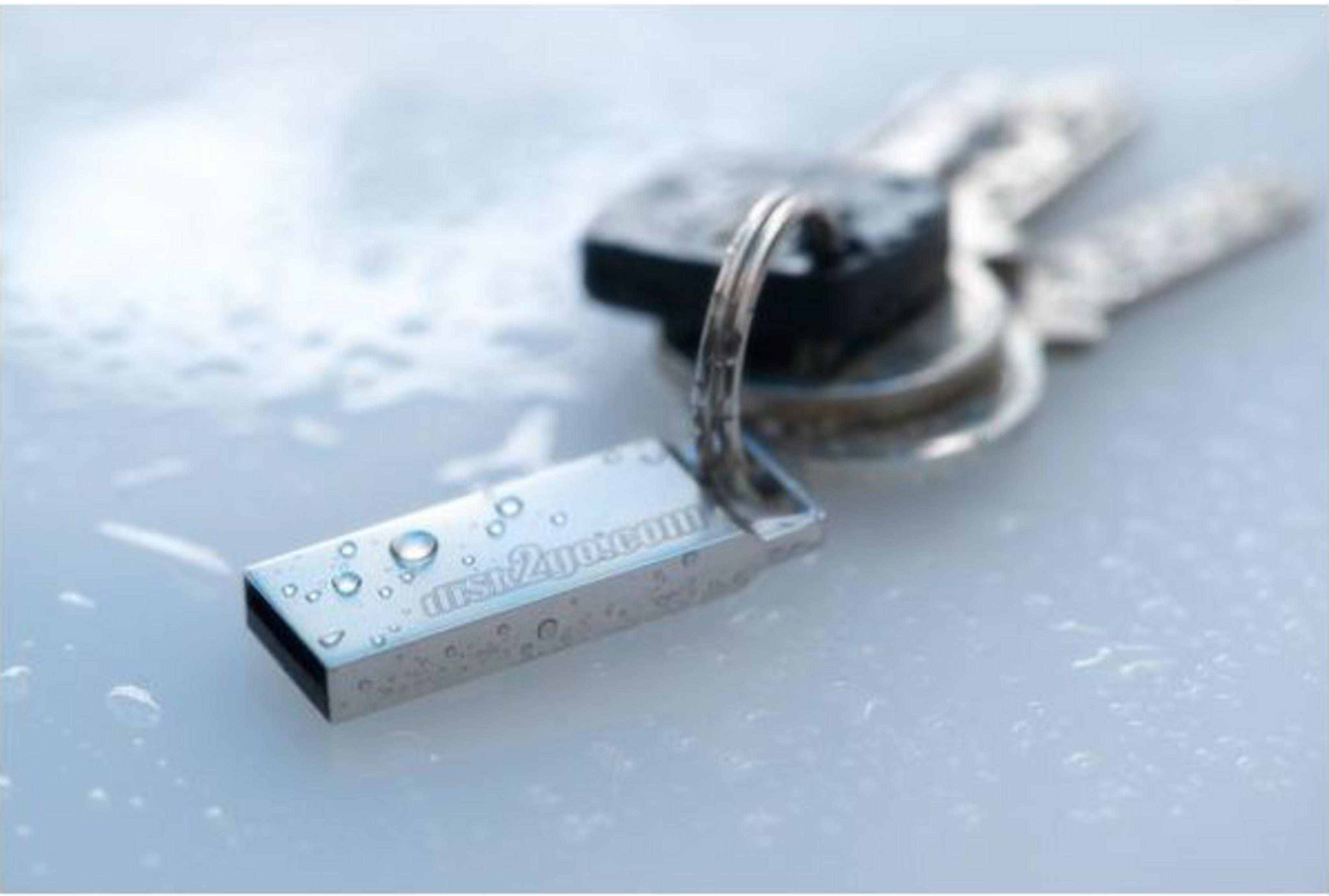 Une clé USB argentée avec des gouttes d'eau et des clés sur une surface mouillée.