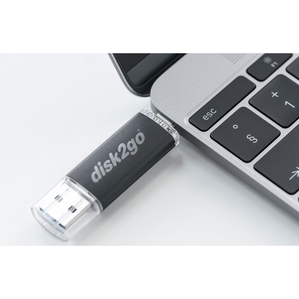 Une clé USB disk2go noire est branchée sur le clavier d'un ordinateur portable argenté. Gros plan.
