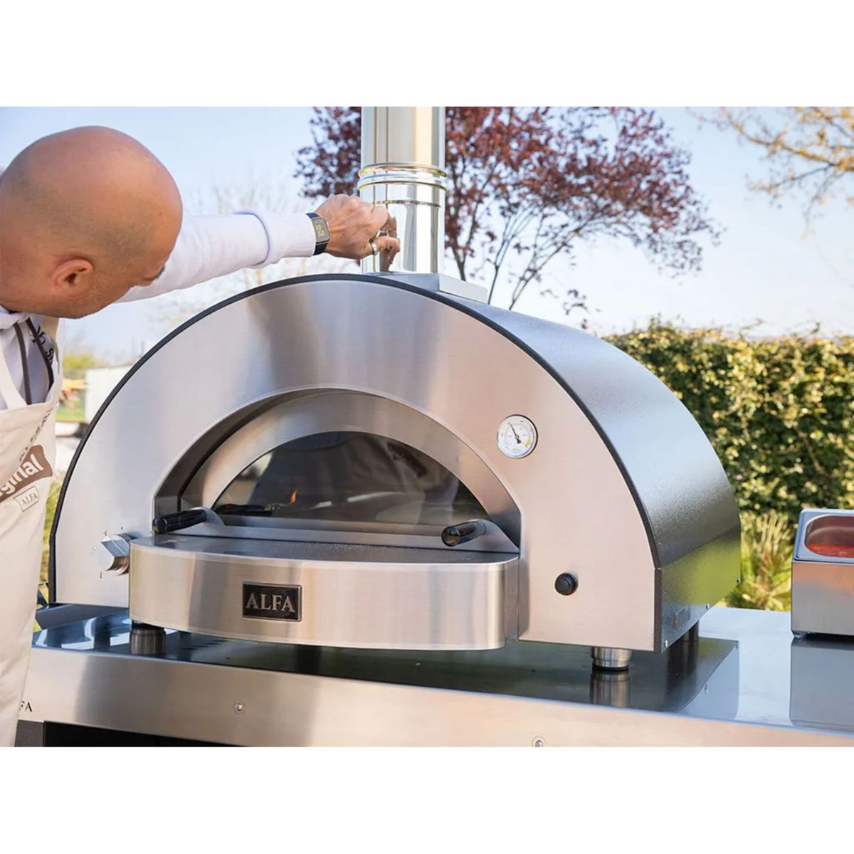 Ein Mann stellt den Schornstein eines modernen Pizzaofens ein.