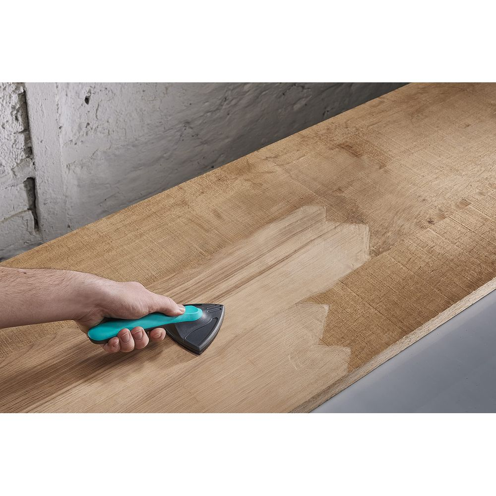 Une main utilise un outil pour lisser une surface en bois.