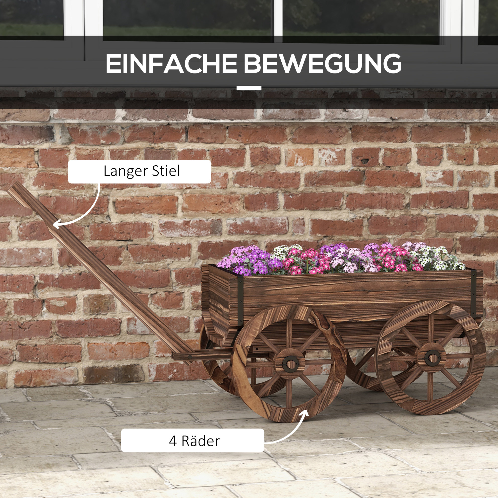 Holzwagen mit Blumen, langer Stiel und vier Räder vor einer Ziegelwand.