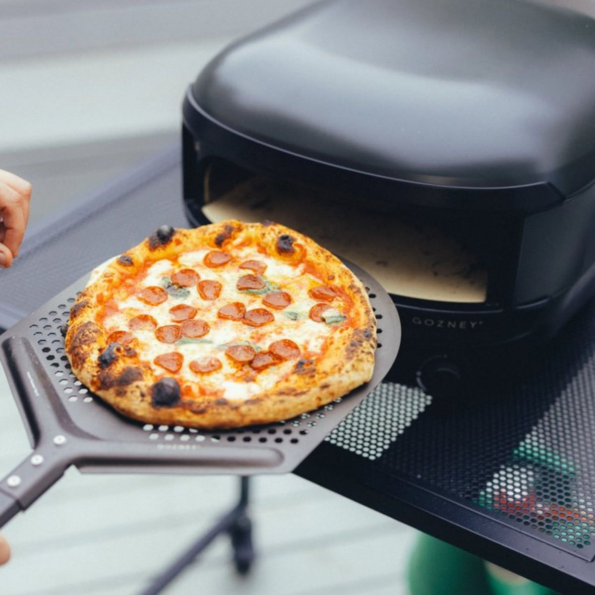 Eine Peperoni-Pizza wird aus einem Pizzaofen auf einer Schaufel genommen.