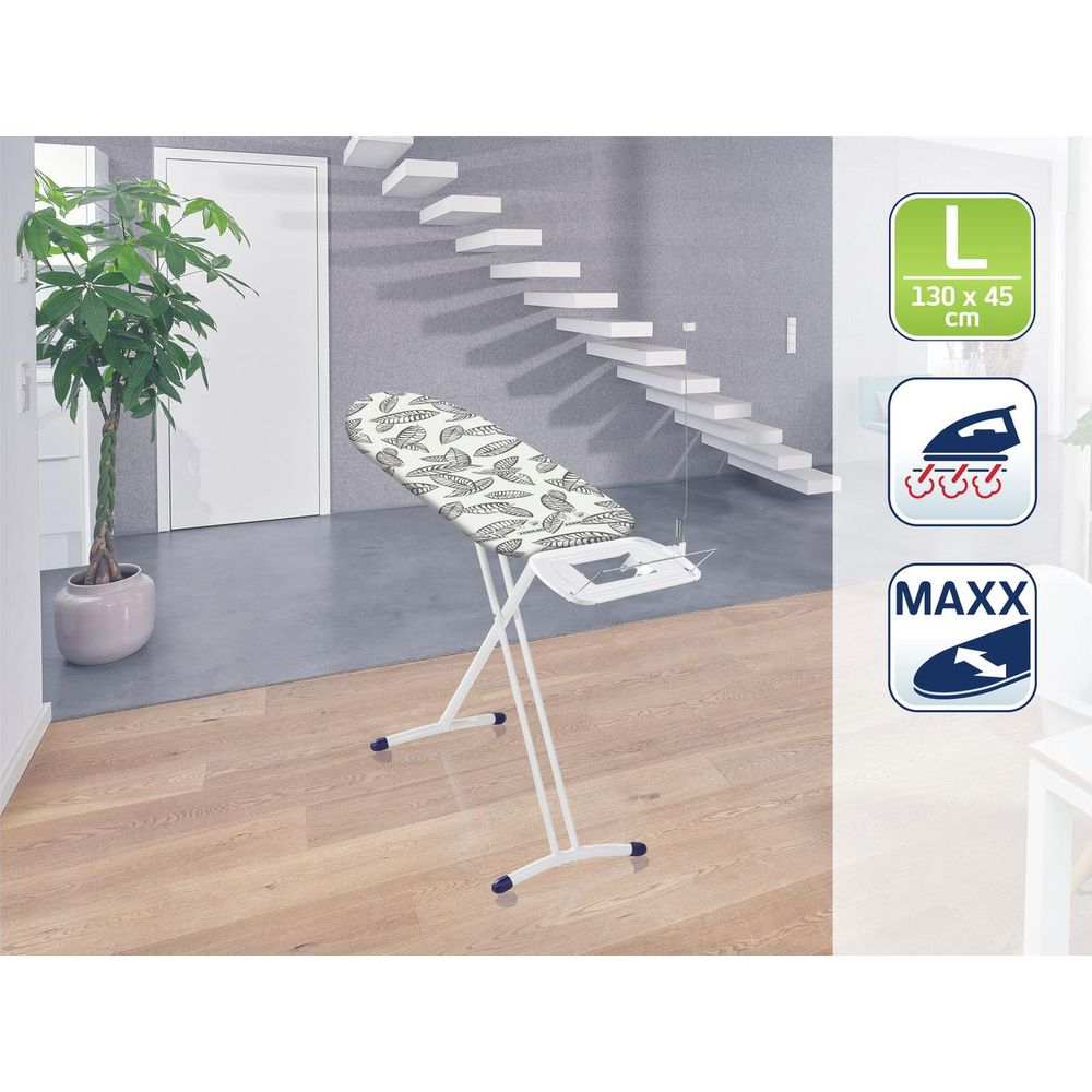 Deska do prasowania we wzór liści stoi na drewnianej podłodze obok rośliny.