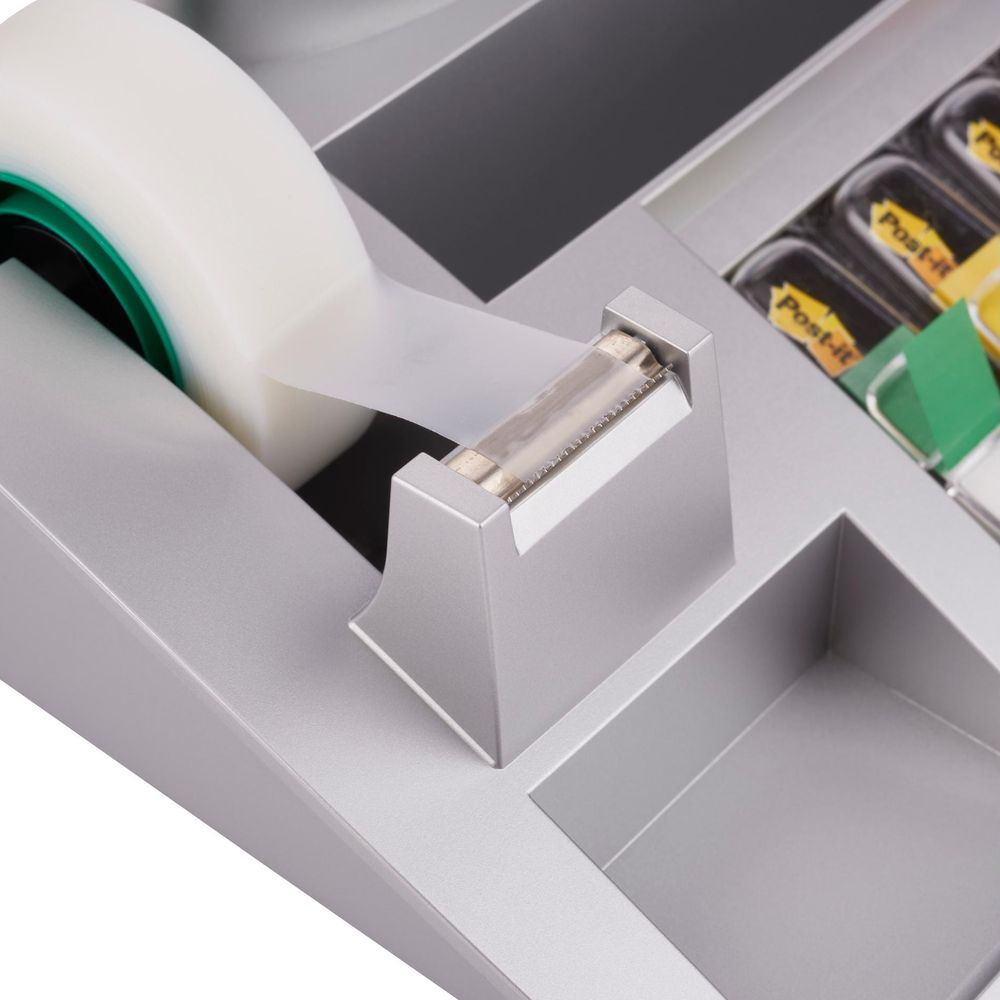 Un dispenser di nastro adesivo argentato con nastro e note Post-it.