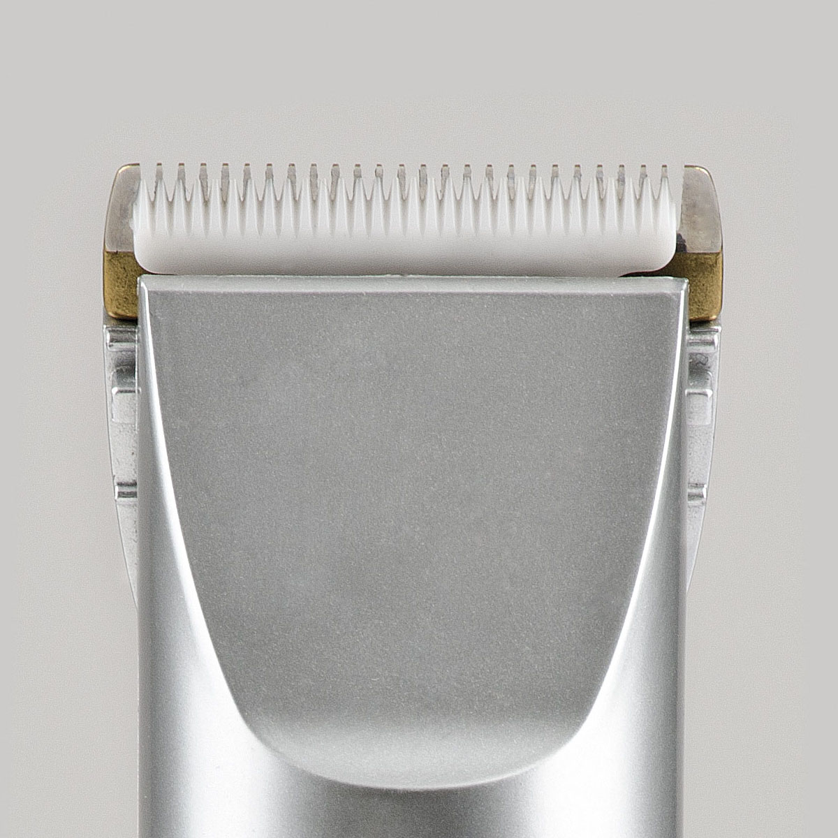 Primo piano di un tagliacapelli argentato con denti bianchi e accenti dorati.