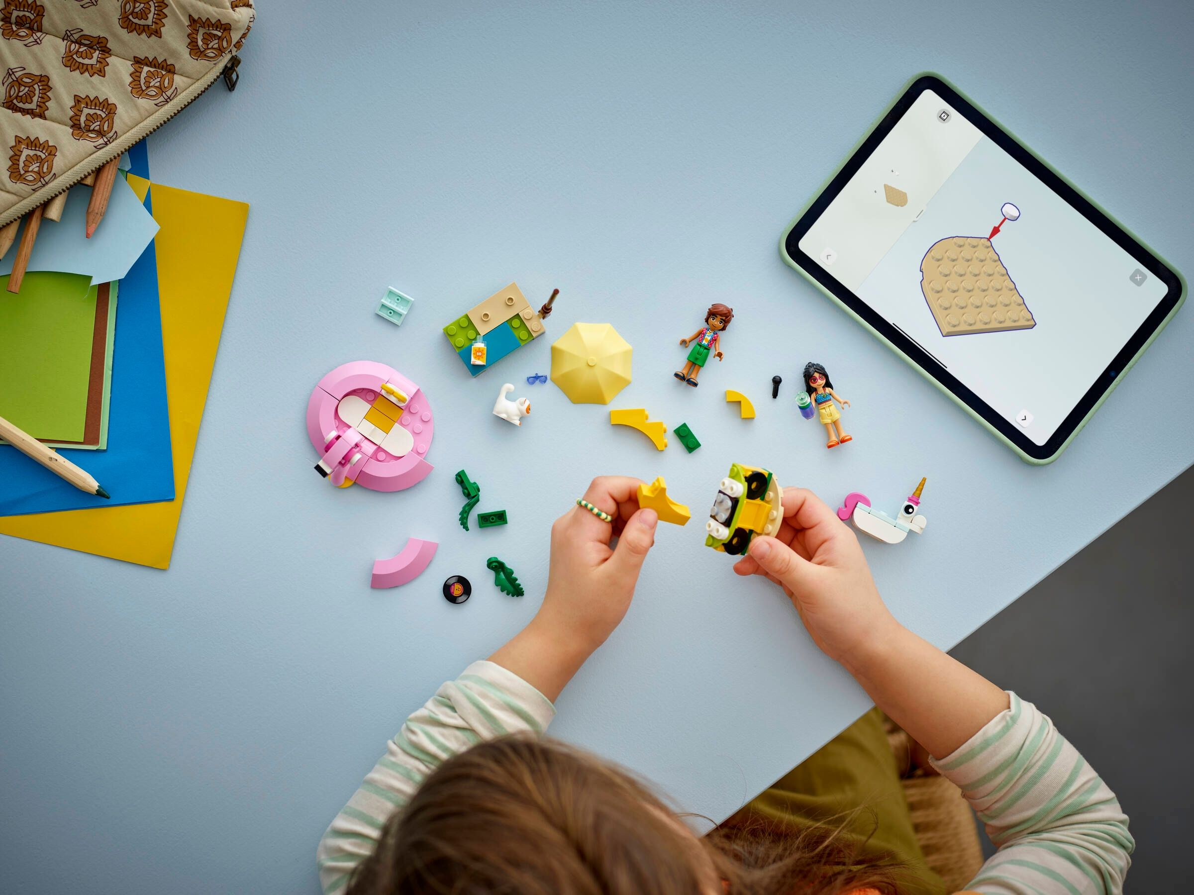 Ein Kind baut mit bunten Legosteinen und schaut auf ein Tablet.