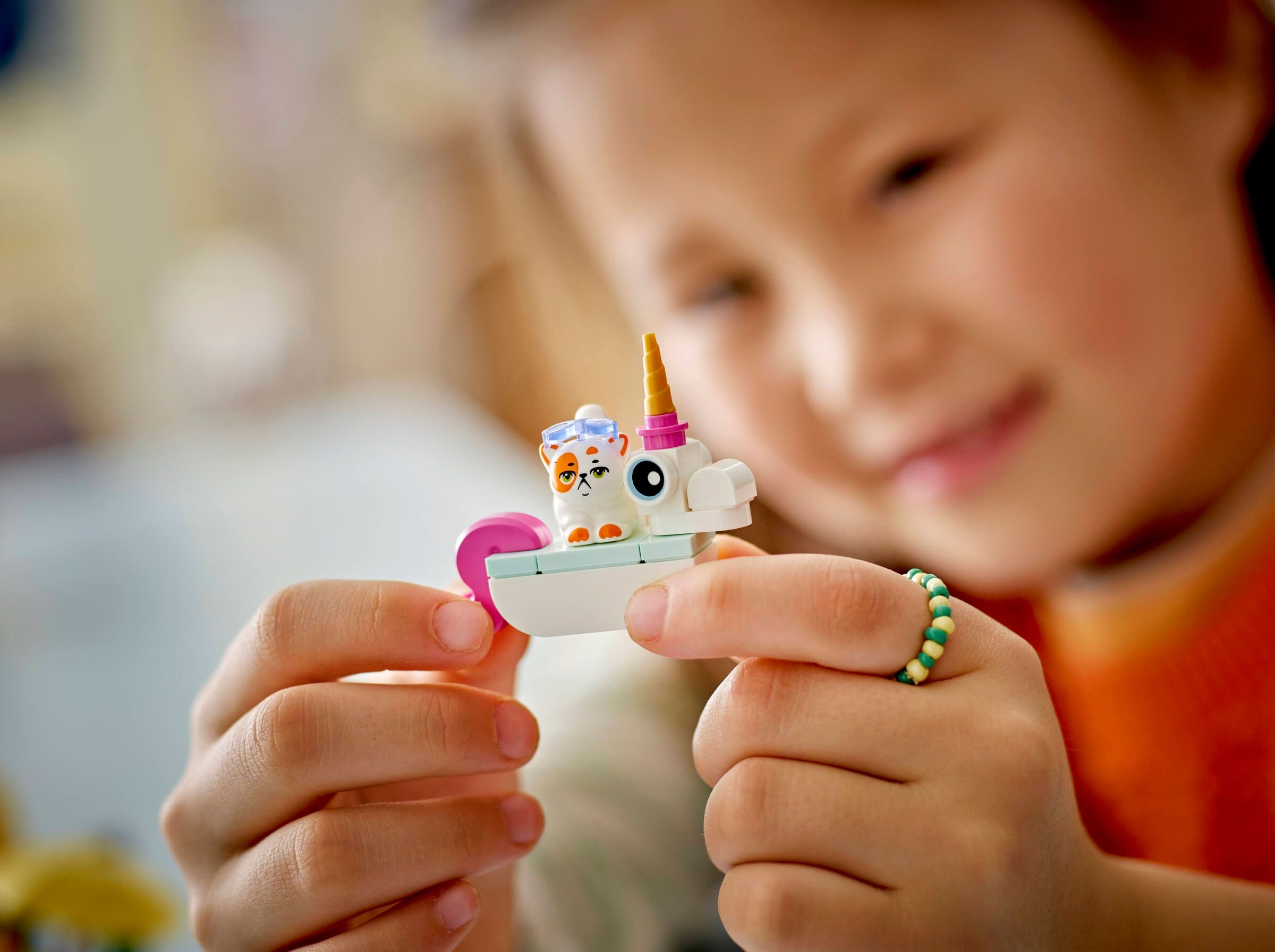 Ein Kind hält ein Lego-Spielzeug eines weißen Katers mit blauen Brillen und einem Einhorn.