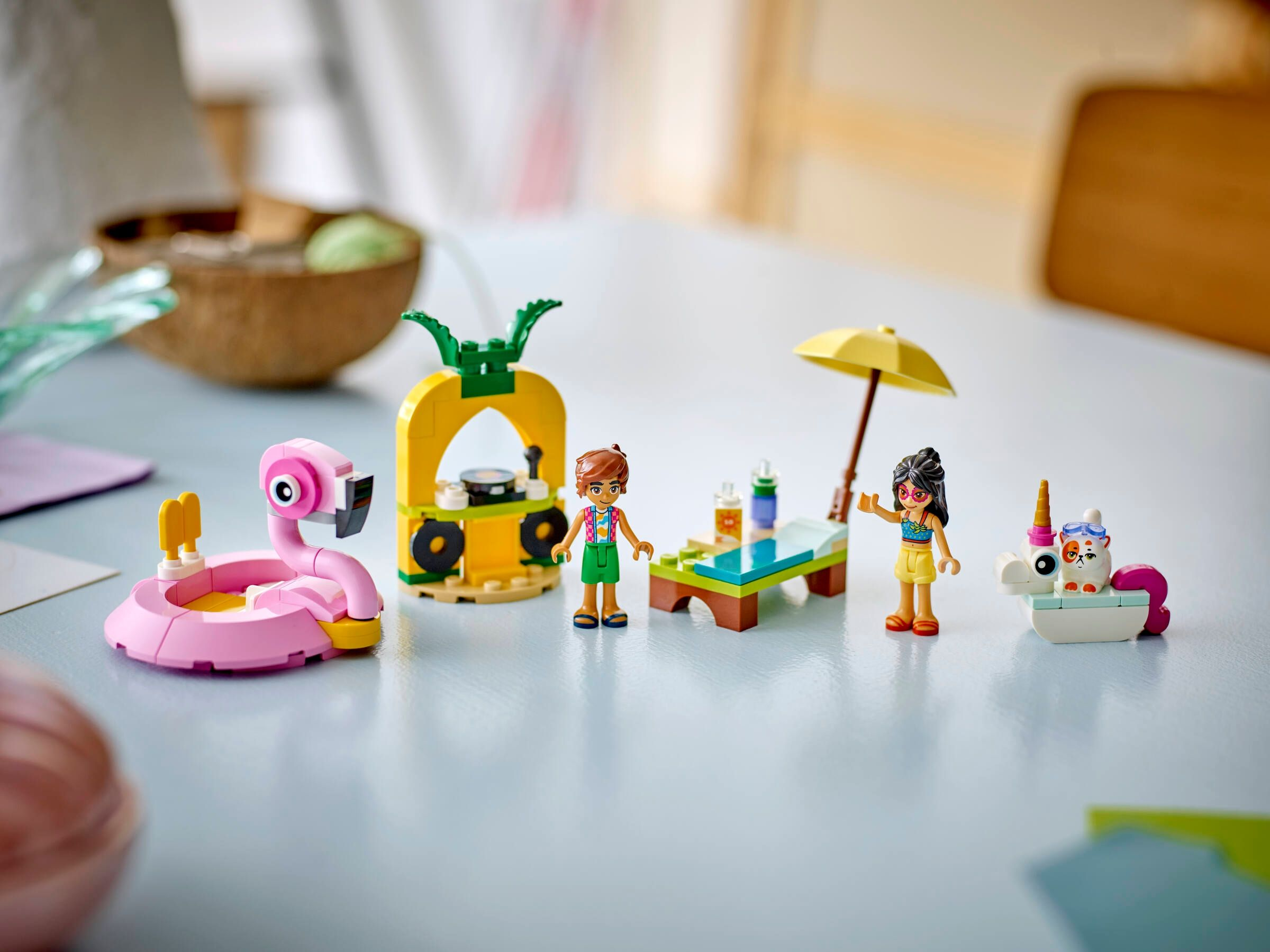 Spielzeugfiguren am Strand: Flamingo-Pool, Ananas-DJ, Liege mit Sonnenschirm und Katze.