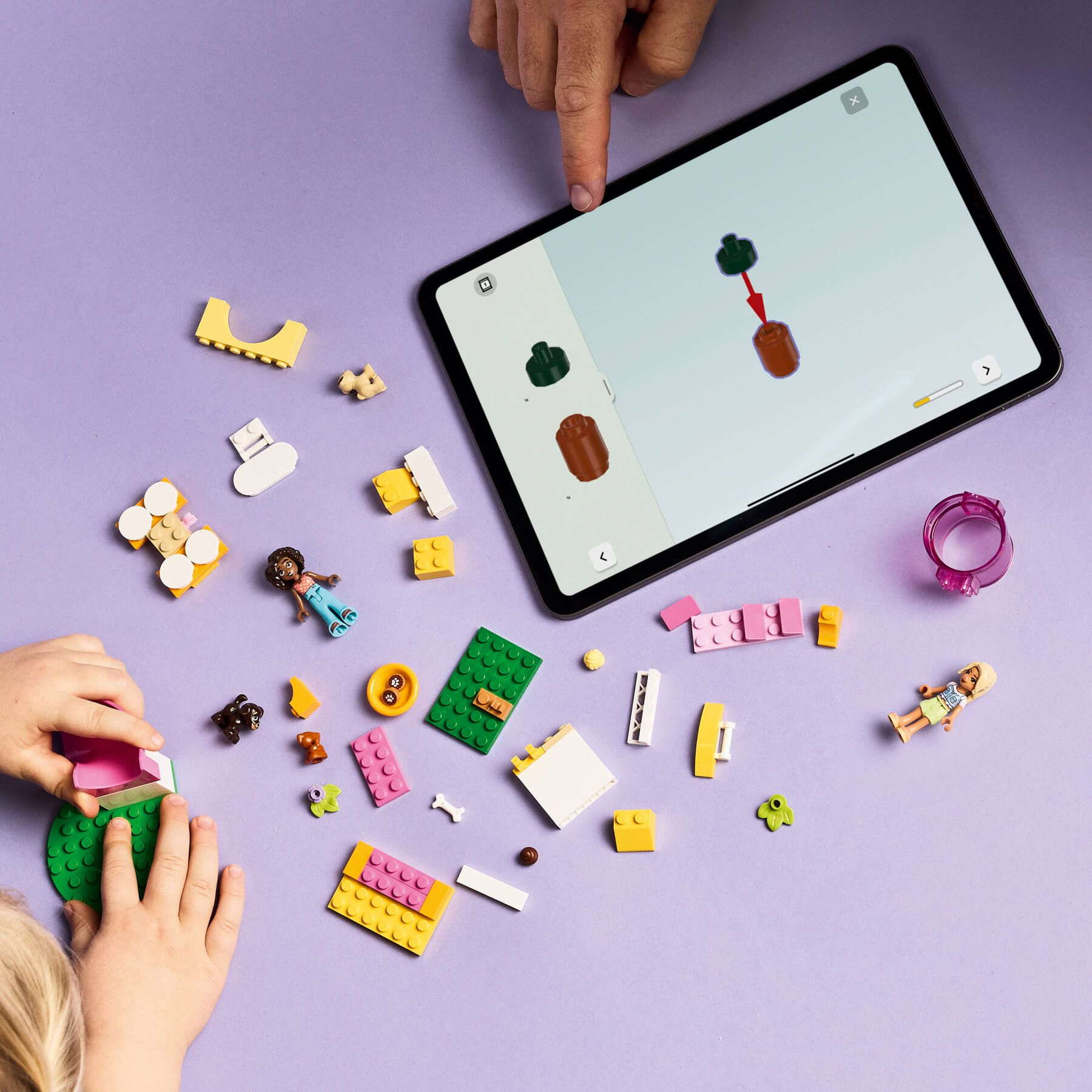 Kinder bauen mit Legosteinen und einem Tablet, das eine Bauanleitung zeigt.