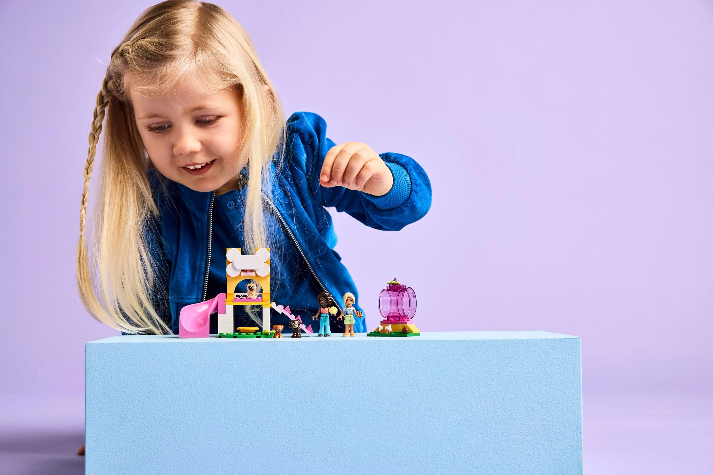 Ein kleines Mädchen spielt mit Lego-Figuren und einem Spielset.