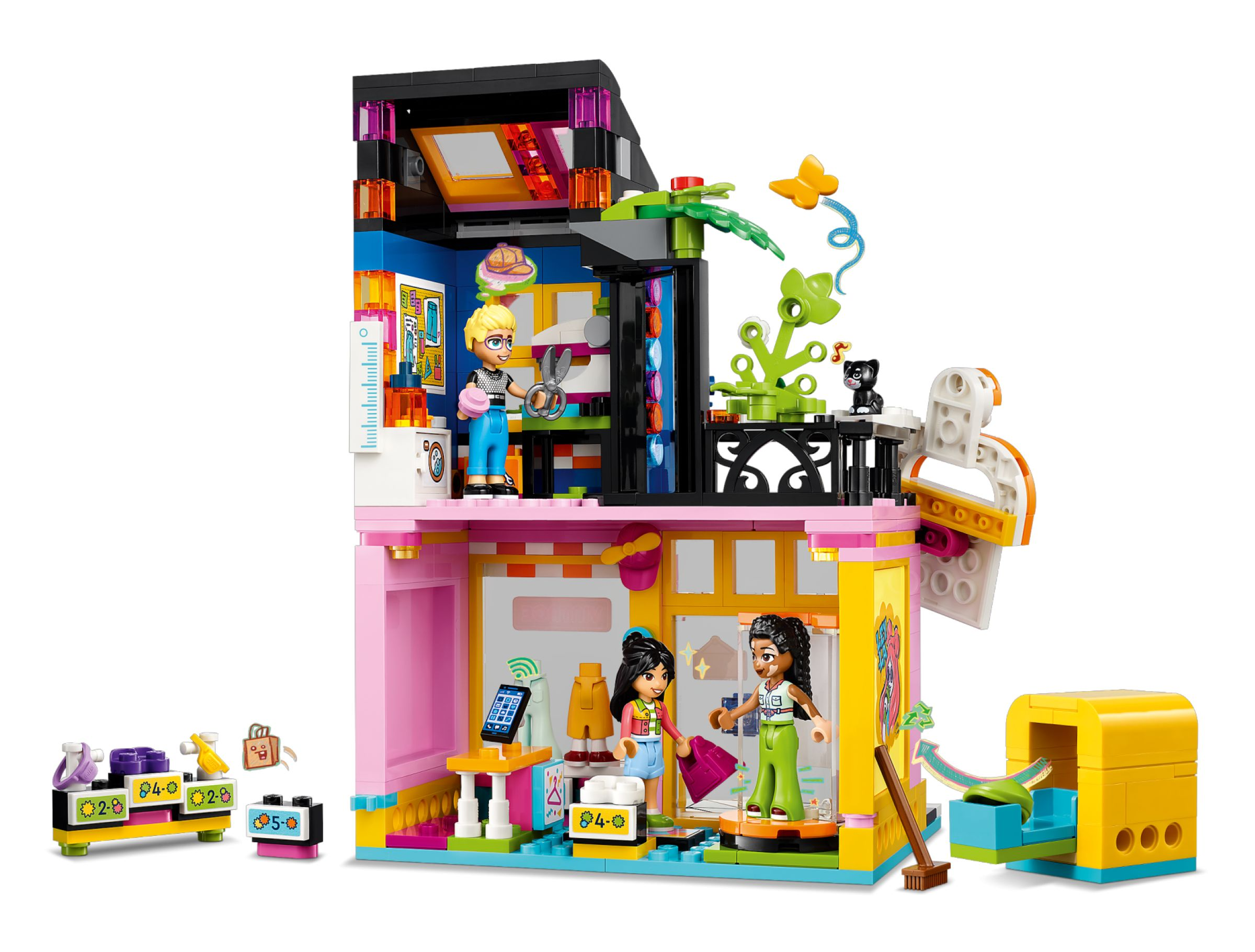 Ein LEGO-Modell eines Geschäfts mit zwei Spielfiguren, einem Kätzchen und einem gelben Automaten.
