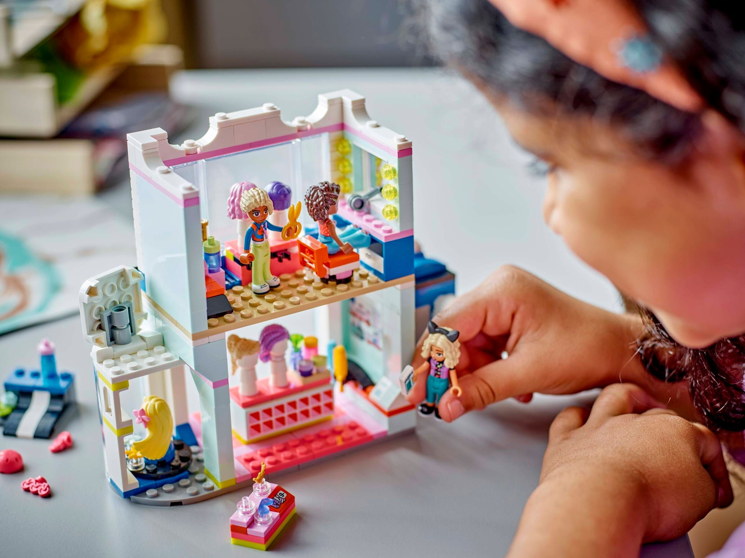 Ein Kind spielt mit einem Lego-Friseursalon-Set mit Figuren und Zubehör.