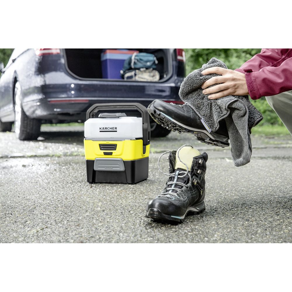 Persona asciuga stivali vicino a dispositivo Karcher con bagagliaio aperto.