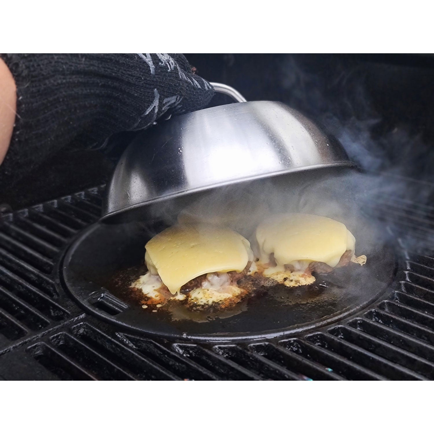 Twee cheeseburgerpatties smelten op een grill, met opstijgende stoom.
