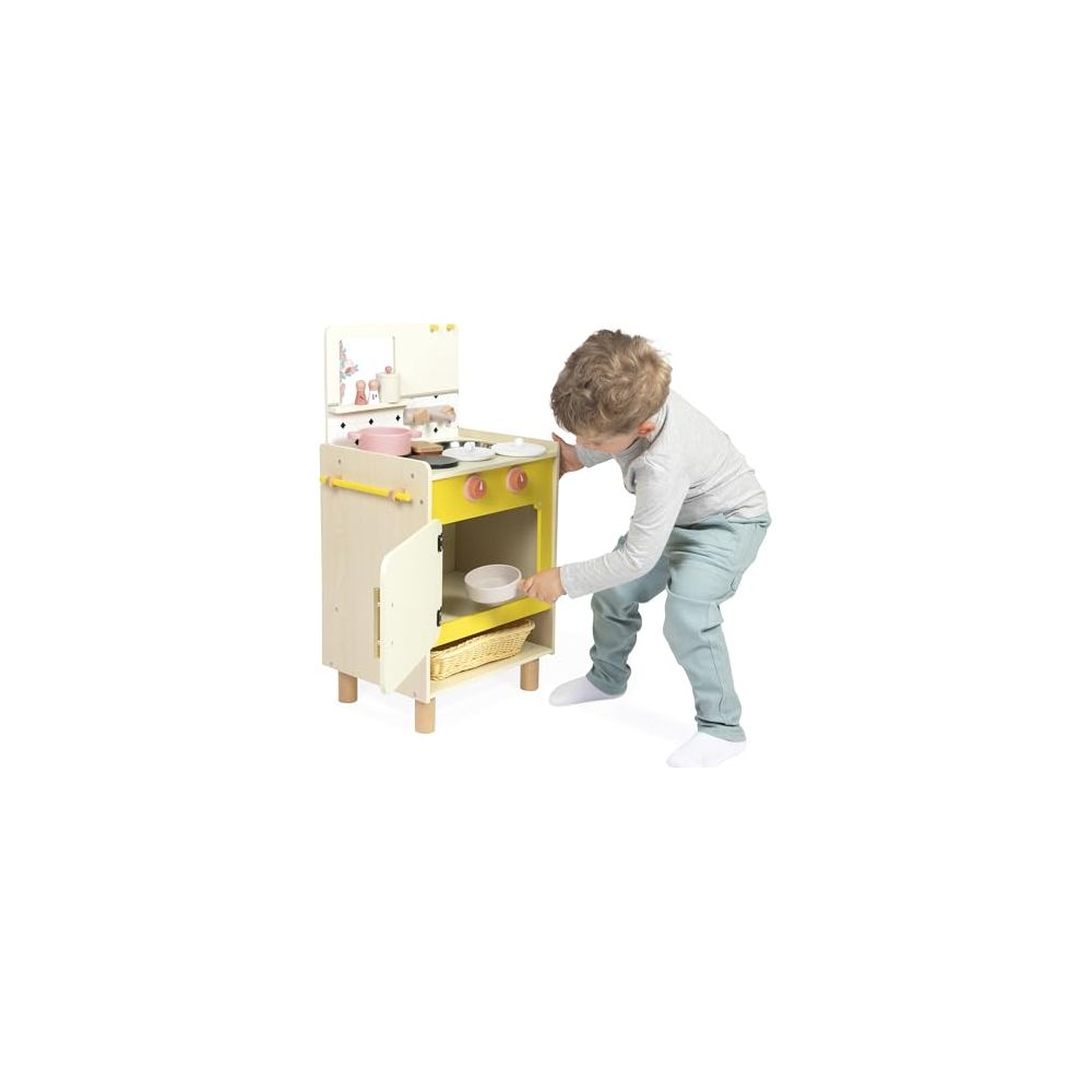 Ein Junge spielt mit einer Holzspielküche mit rosa Kochutensilien und Geschirr.