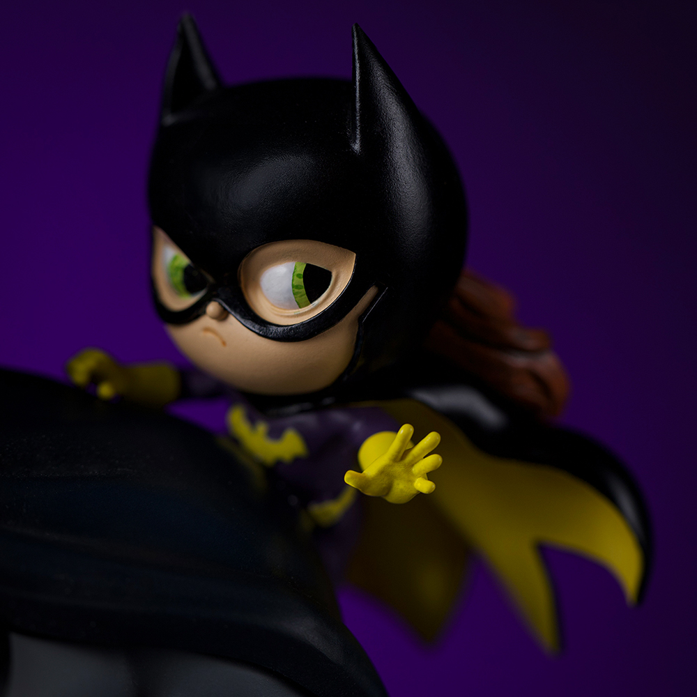 Eine Spielzeugfigur von Batgirl mit gelben Handschuhen und Umhang.