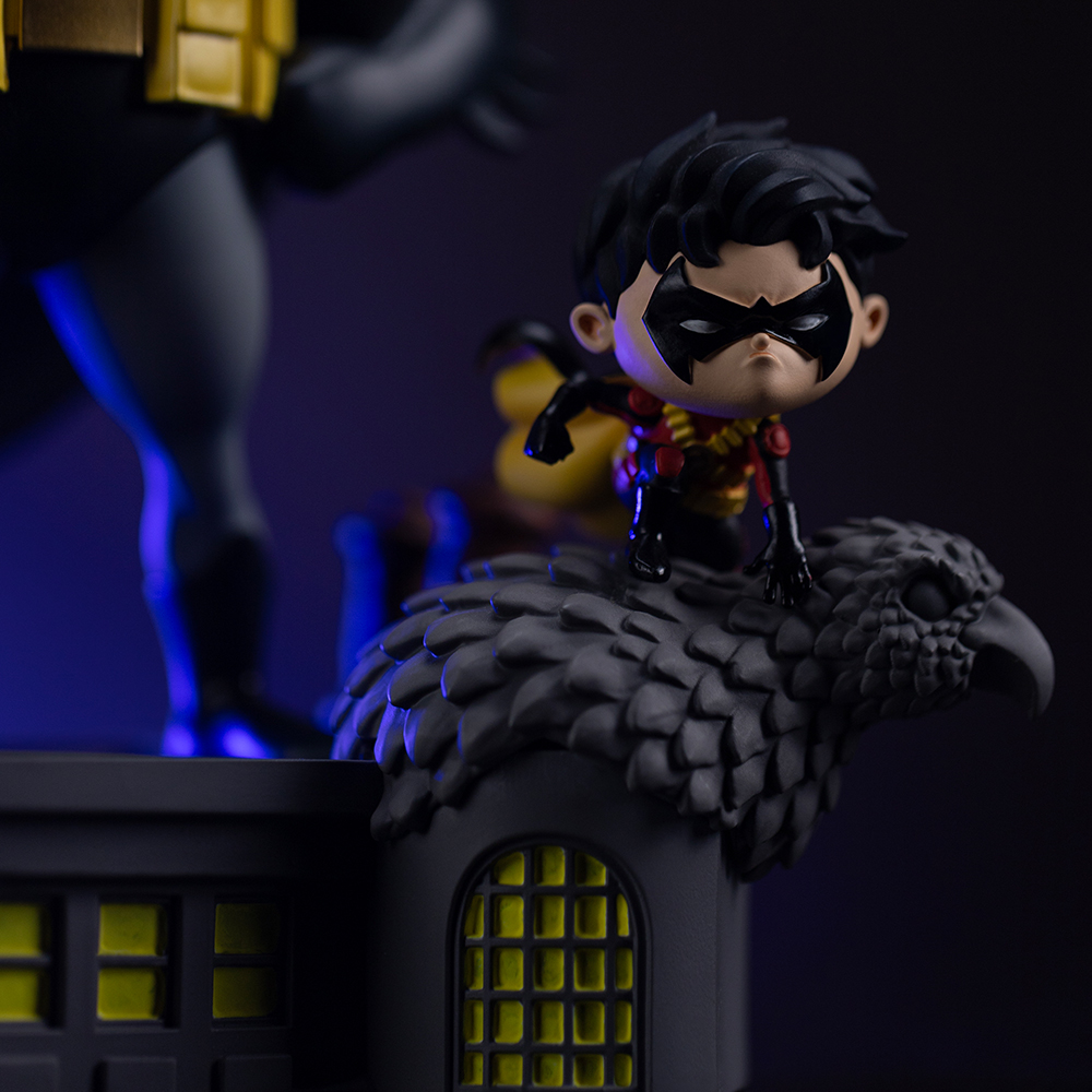 Robin-Figur auf einem Adler-Sockel vor Batman-Figur.