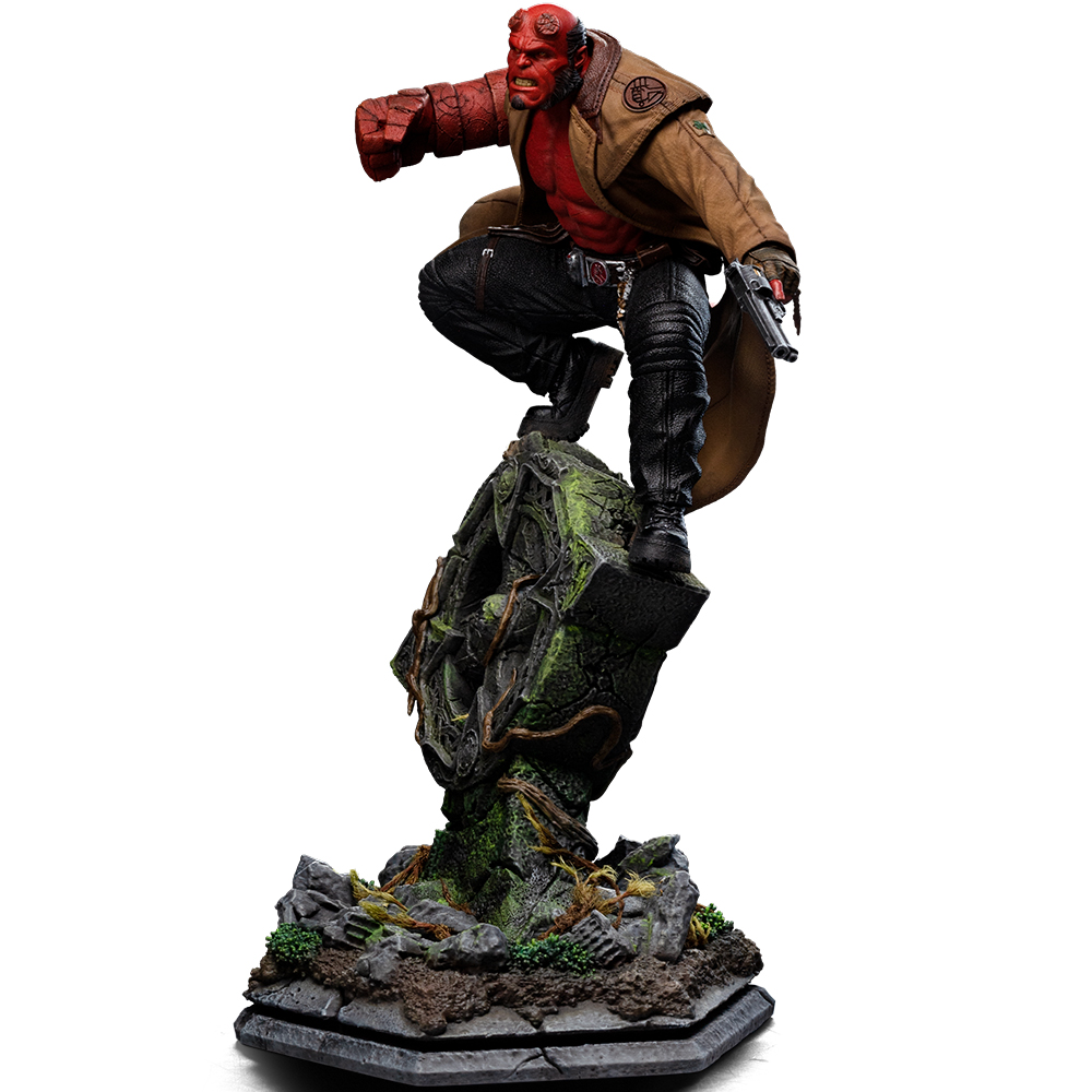 Hellboy-Figur in Aktion auf einem moosbewachsenen Sockel mit Waffe.