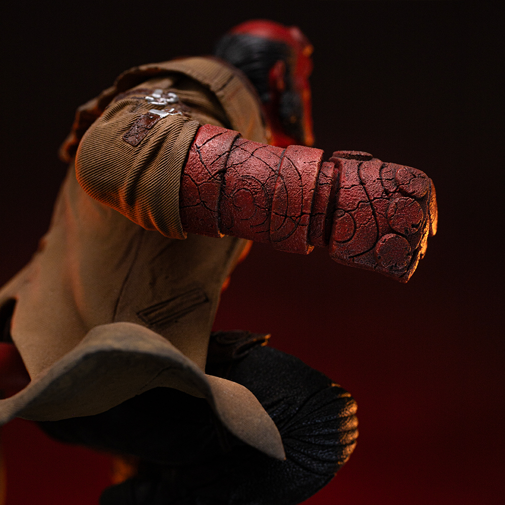 Eine Figur von Hellboy in einem braunen Mantel mit einem roten, steinigen Arm, der nach vorne geballt ist.