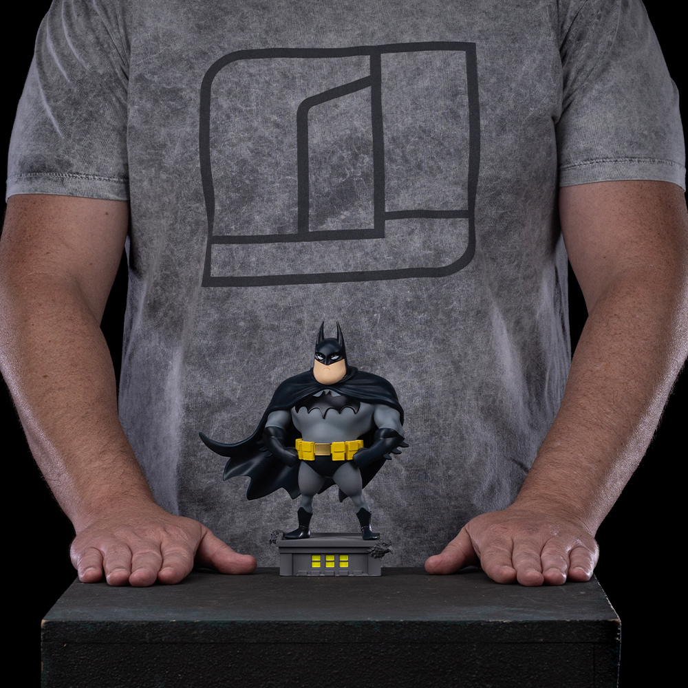Eine Batman-Figur steht auf einem Sockel vor einem Mann in einem T-Shirt.