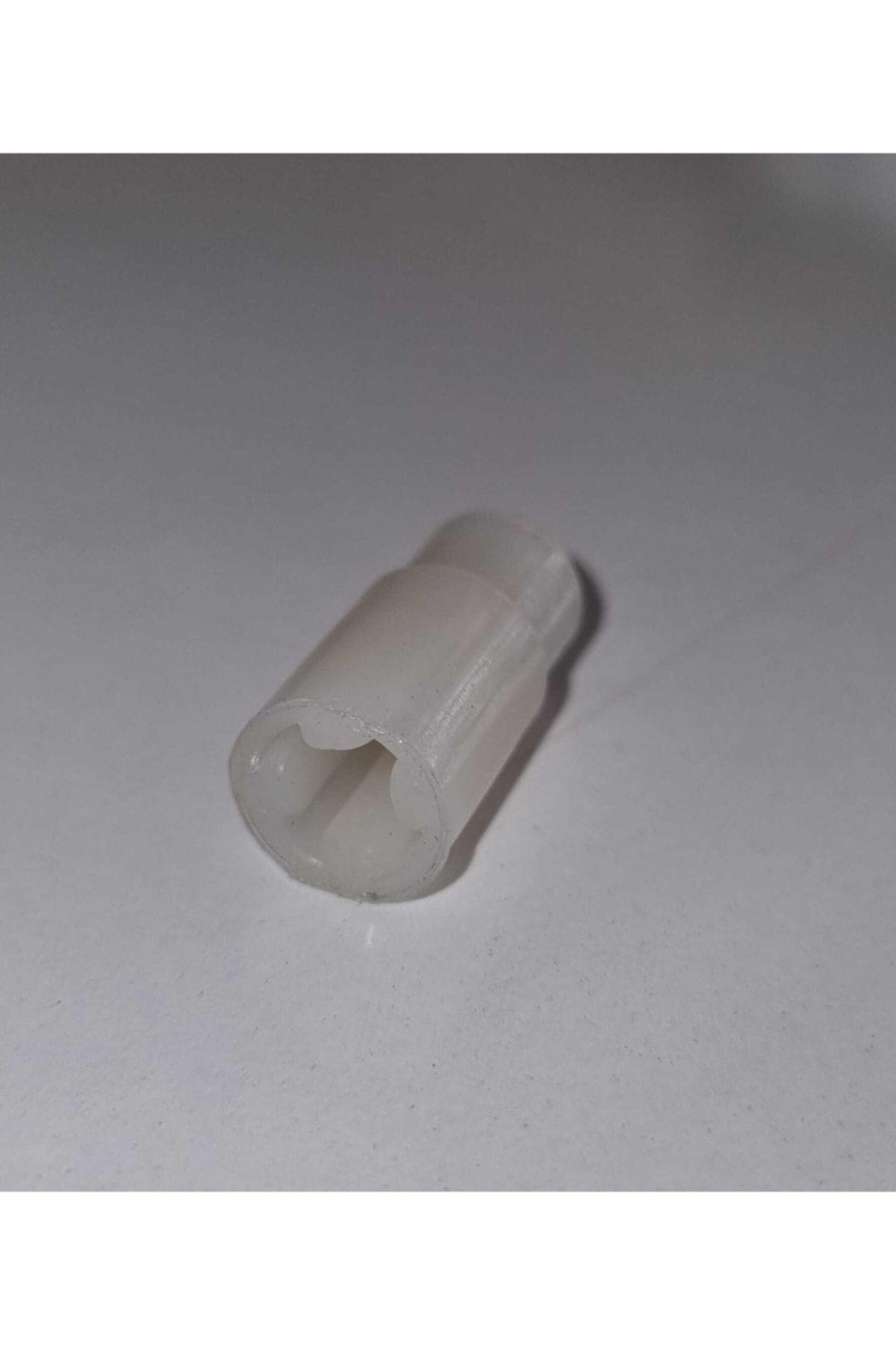 Silindirik gövdeli ve yuvarlak açıklıklı beyaz plastik kapak.