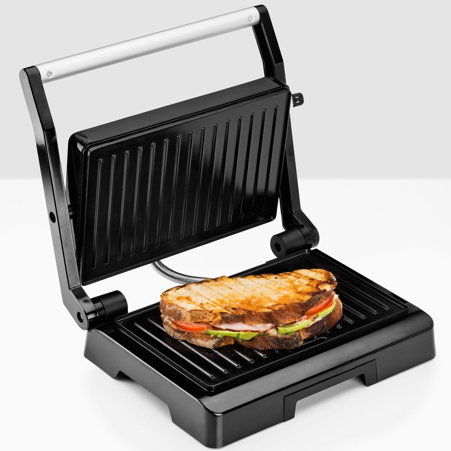 Een geroosterde tosti met ham, tomaat en avocado in een open grill.