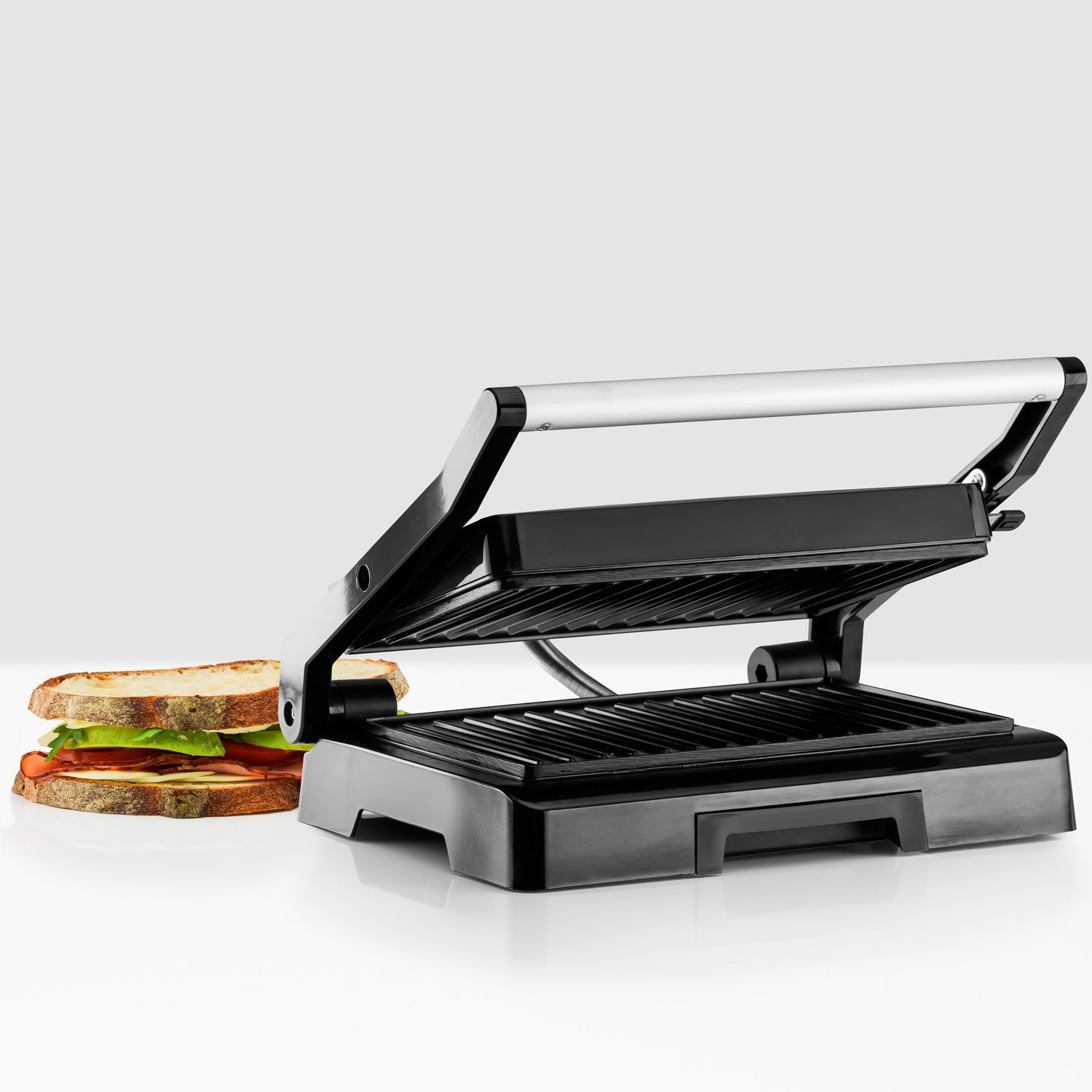Een open tosti-ijzer met een tosti ernaast.