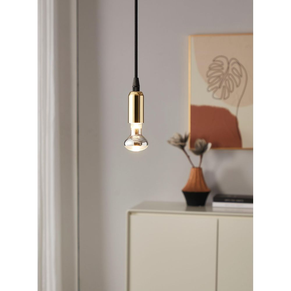 Une lampe suspendue avec base et ampoule dorées au-dessus d'une armoire.